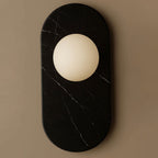 Here this Clérachic wall sconce appears in black marble, its fine white veining framing the frosted glass globe light.