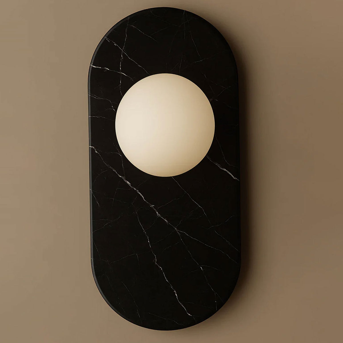 Here this Clérachic wall sconce appears in black marble, its fine white veining framing the frosted glass globe light.