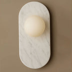 This closer shot of the Clérachic wall sconce shows white marble with soft grey veining wrapped around the glass globe.