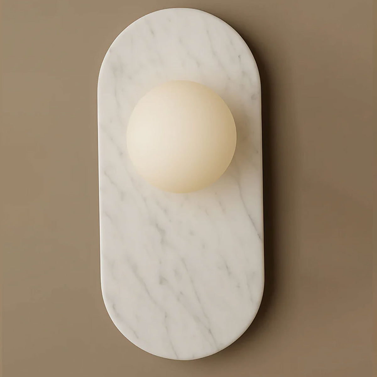 This closer shot of the Clérachic wall sconce shows white marble with soft grey veining wrapped around the glass globe.