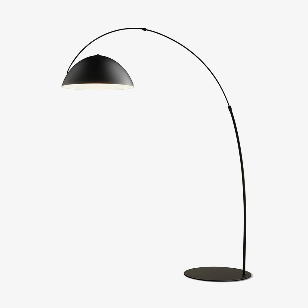 Verse arc floor lamp with tapered black stem beside a reading chair
