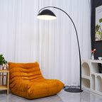 Verse arc floor lamp lit warmly beside a lounge chair