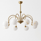 Unlit against a plain white background, this brass Clérachic chandelier's arms arch up and cross overhead in a crown shape.