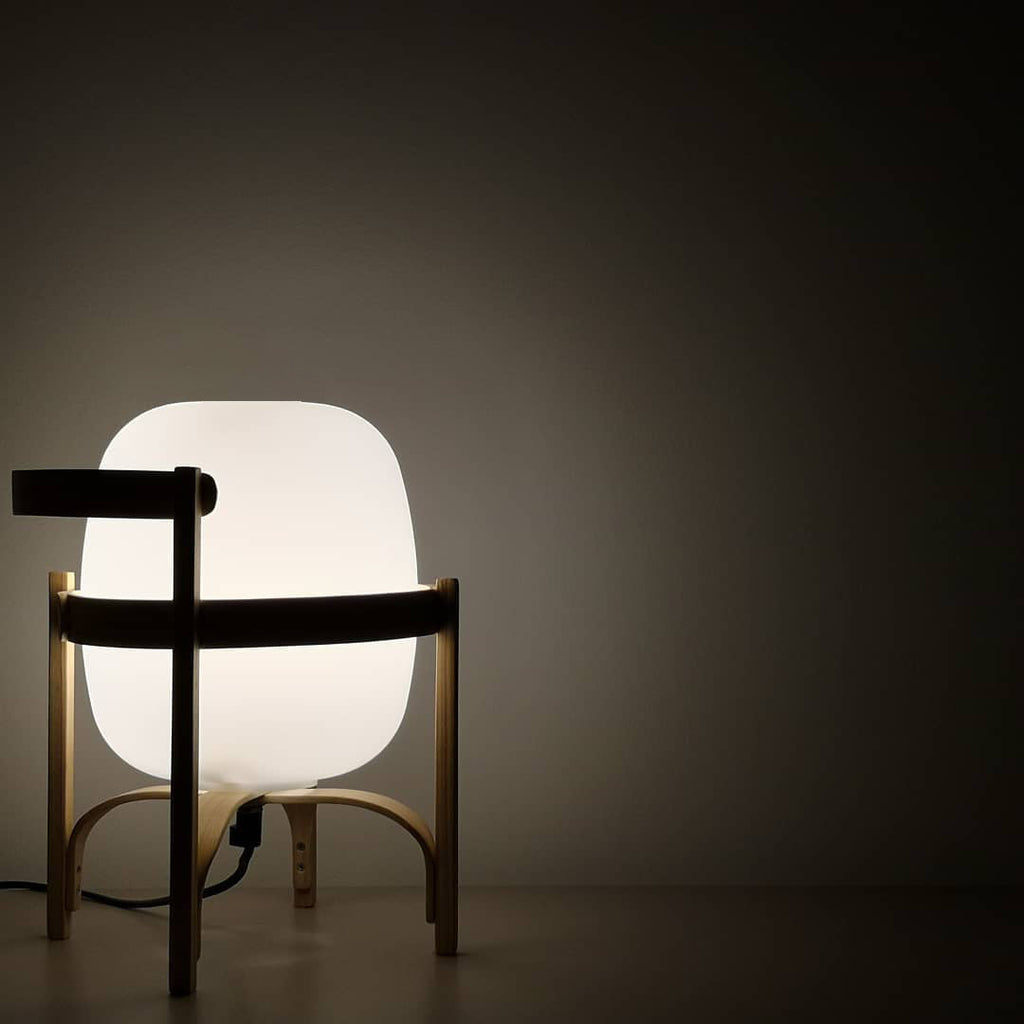 Portable lantern lamp in wood and glass on a sideboard
