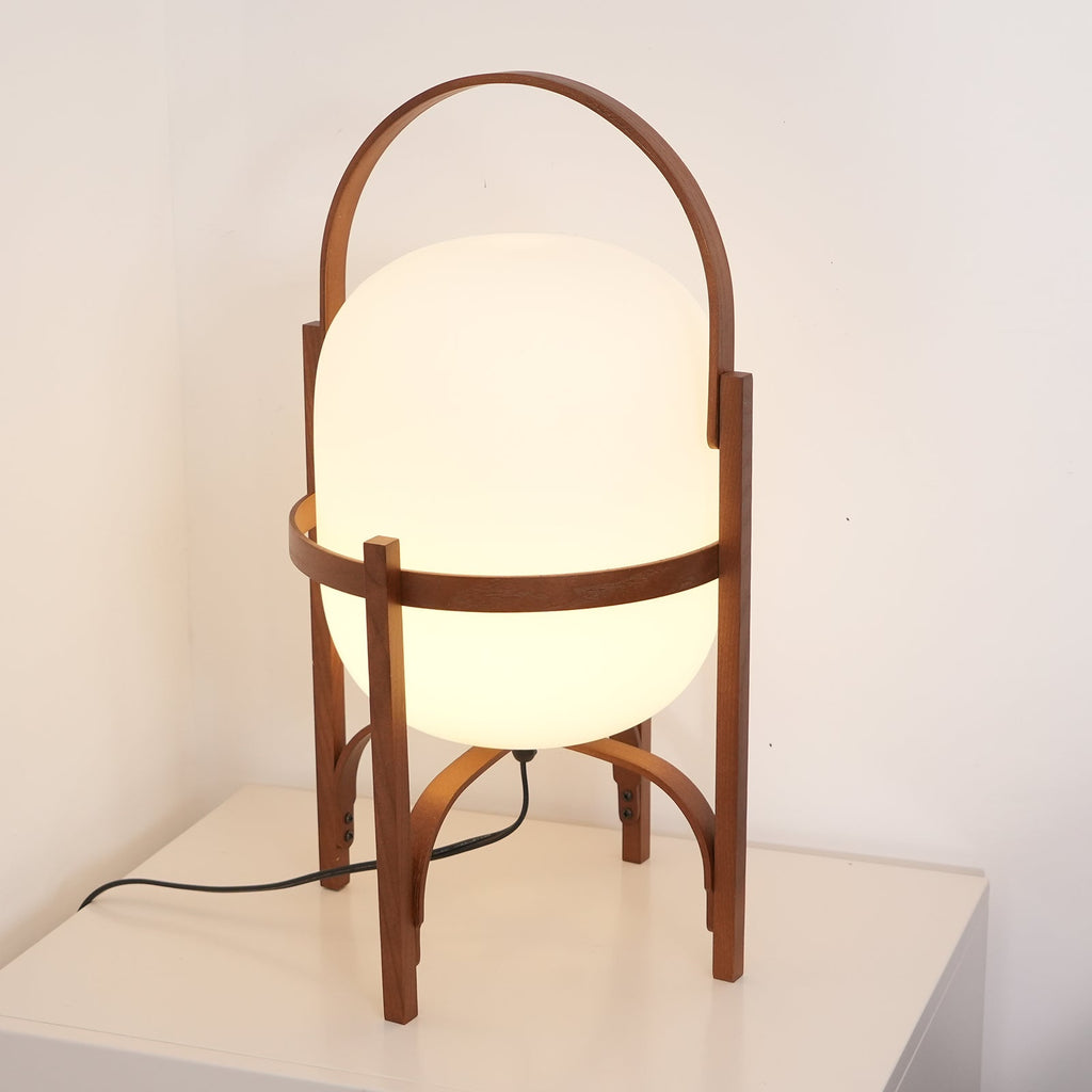 Wood lantern lamp glowing on a floor beside seating