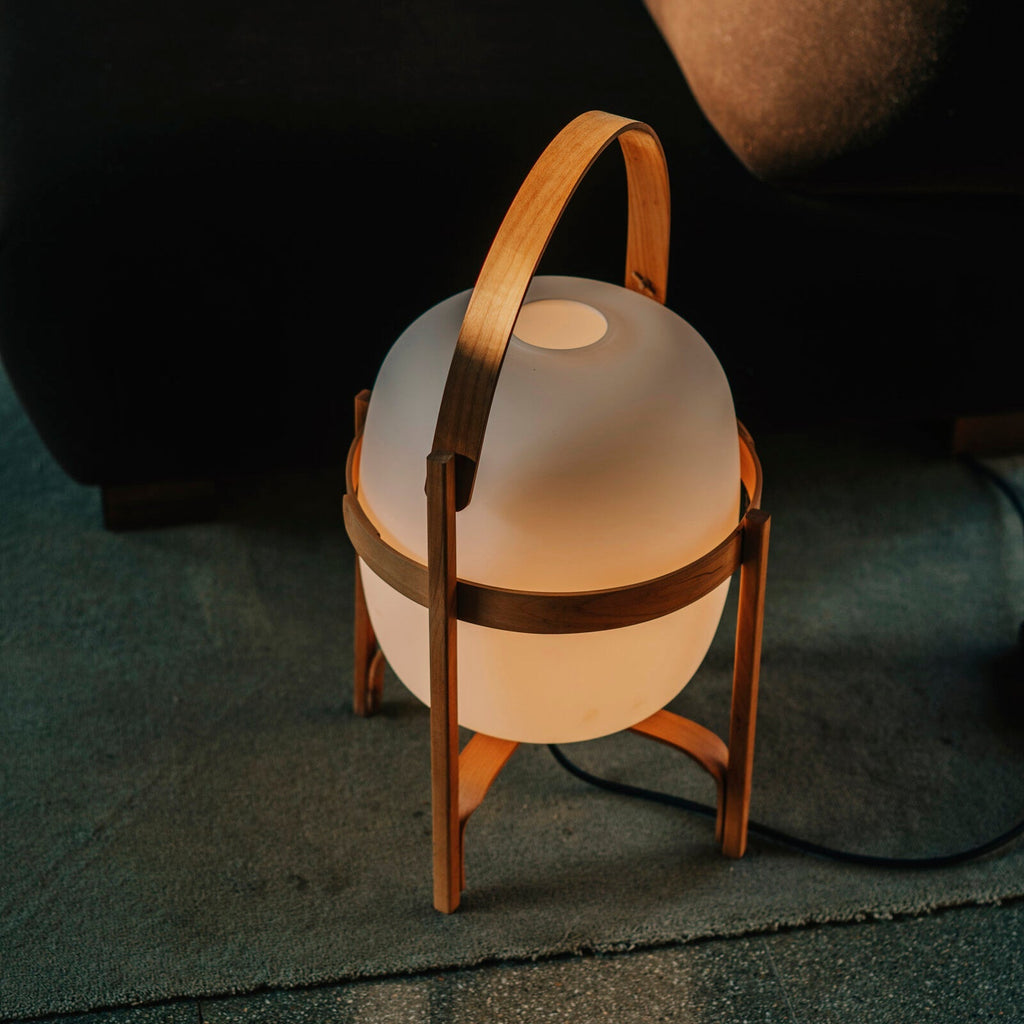 Portable lantern lamp with natural wood frame lit warmly