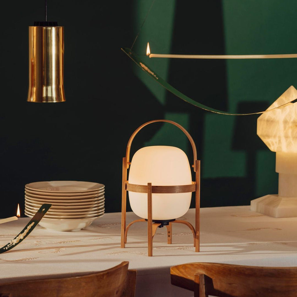 Portable lantern lamp with white glass shade on sideboard