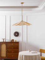 This Clérachic pendant lamp in beige petals hangs on a long brass stem above a walnut sideboard and dining nook.