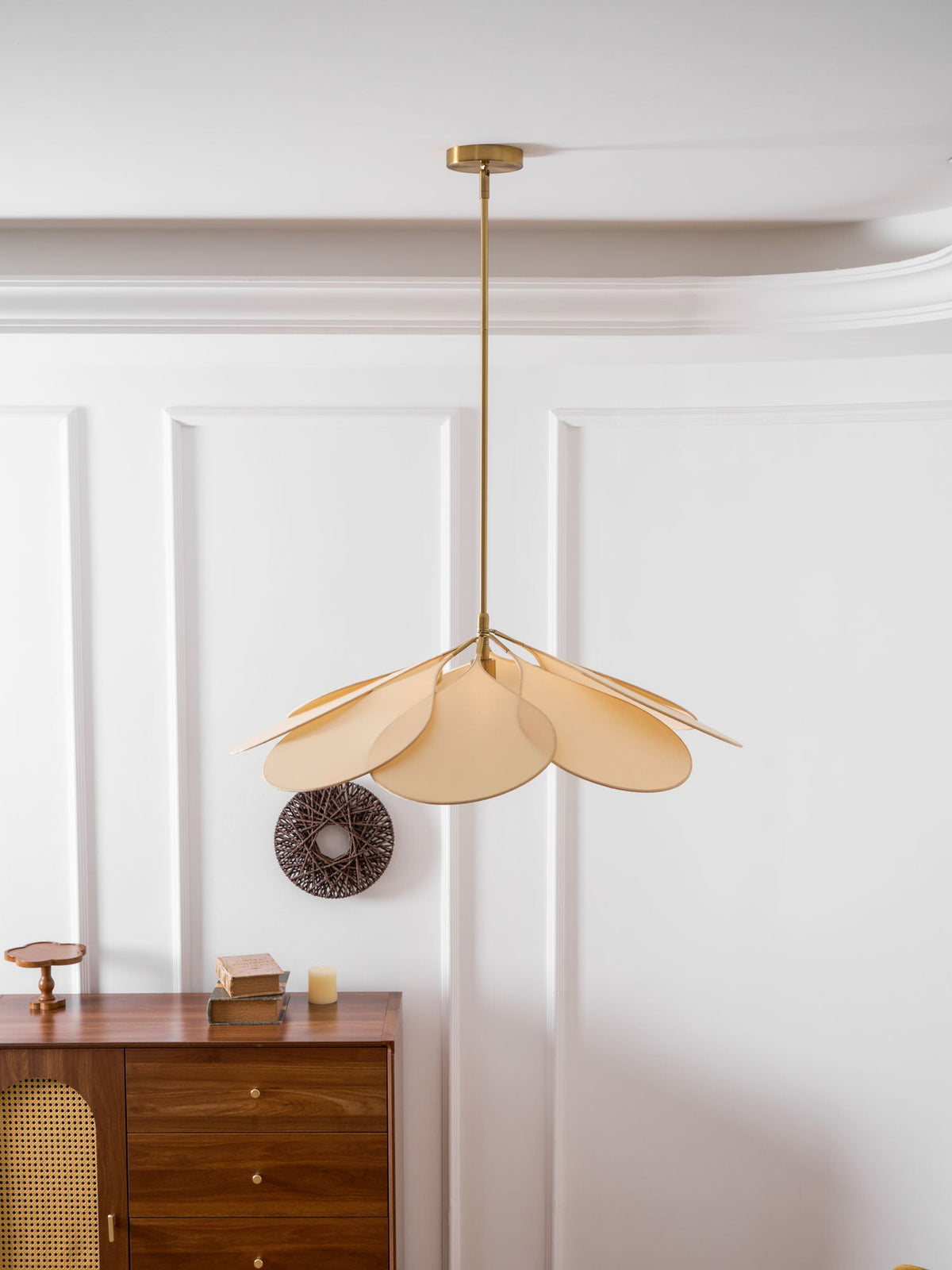 This Clérachic pendant lamp in beige petals hangs splayed loosely to one side, near a walnut sideboard and woven wreath.