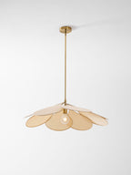 This Clérachic pendant lamp in beige petals hangs low on a brass stem, shown at a slight distance against a plain background.