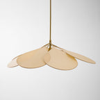 Studio shot of this Clérachic pendant lamp, its beige petals fanned unevenly around a brass fitting on a plain background.