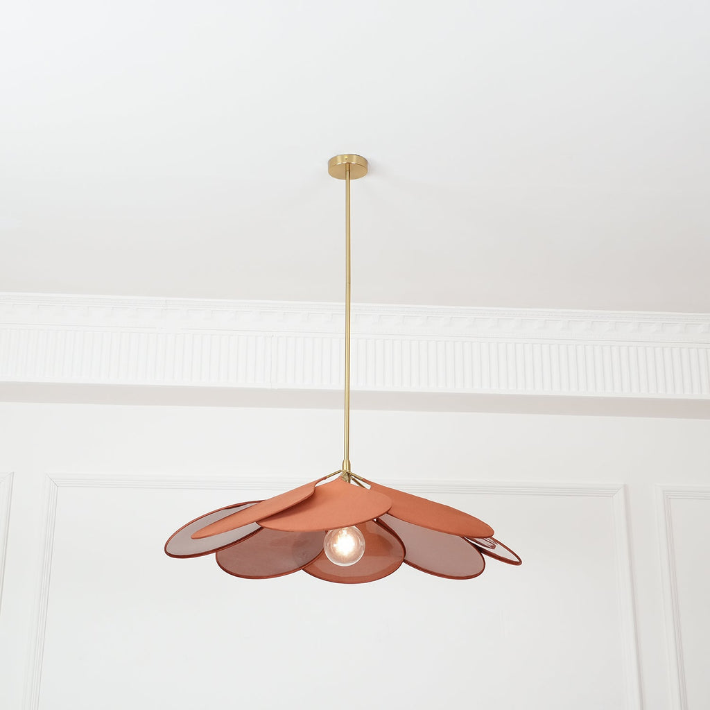 Centred in a panelled room, this Clérachic pendant lamp shows terracotta petals with its bulb glowing beneath.