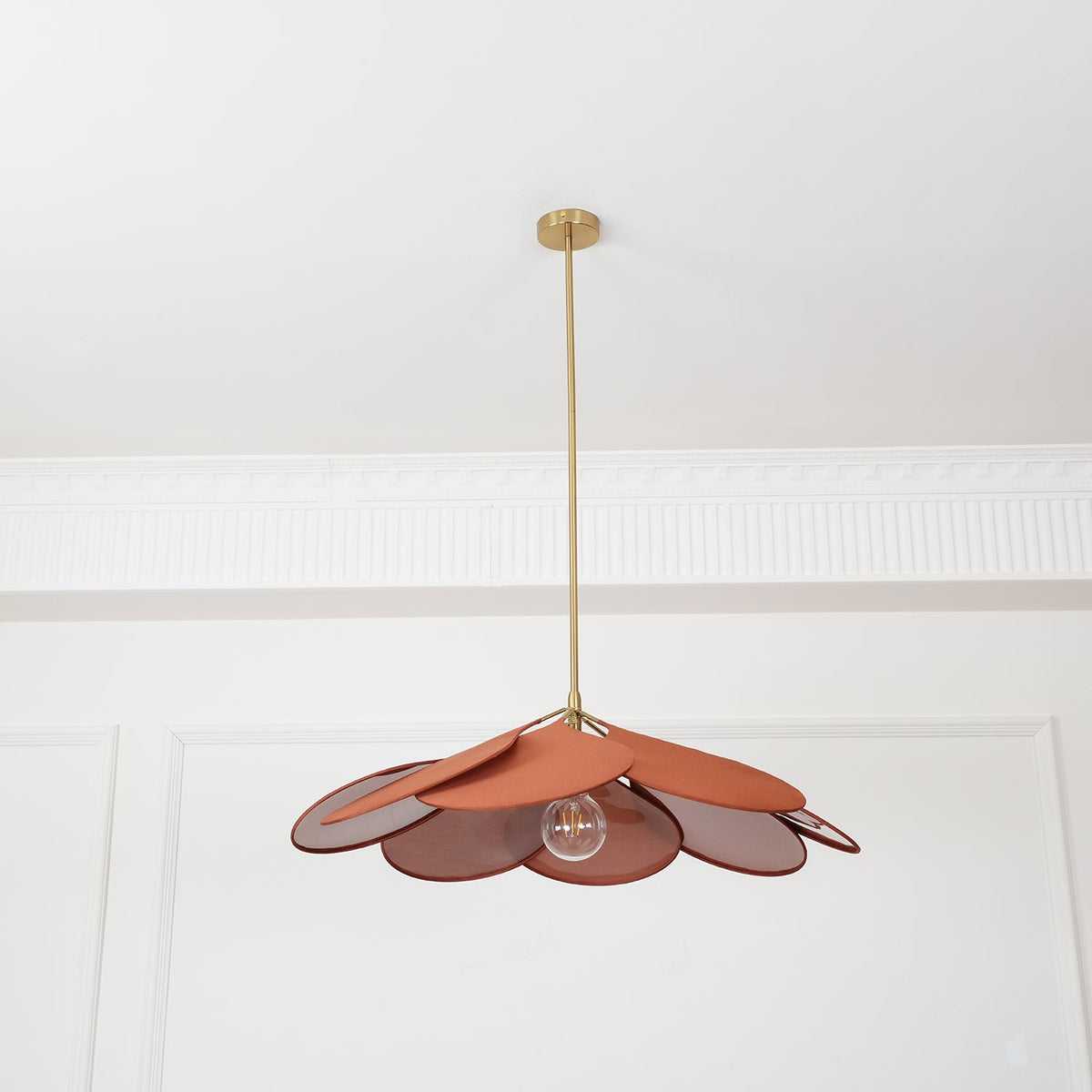 This Clérachic pendant lamp's terracotta petals are shown close beneath the ceiling, with its bulb visible among the fanned shade.