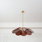 This Clérachic pendant lamp in deep rust petals hangs low, its bulb glowing beneath the fanned shade.