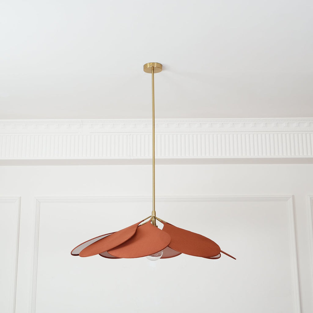 This Clérachic pendant lamp in terracotta petals hangs high on a long brass stem, splayed loosely to one side.
