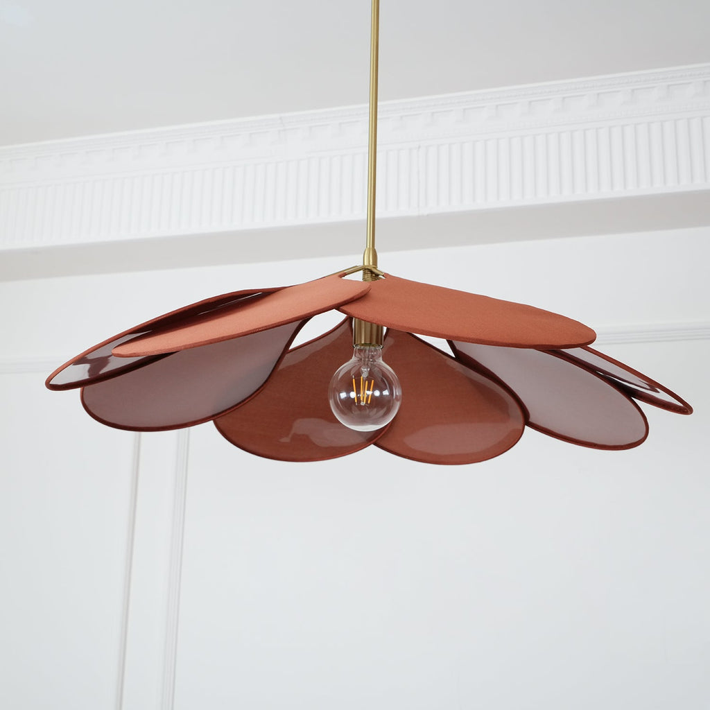 Seen from directly below, this Clérachic pendant lamp's terracotta petals fan out around a glowing bulb.