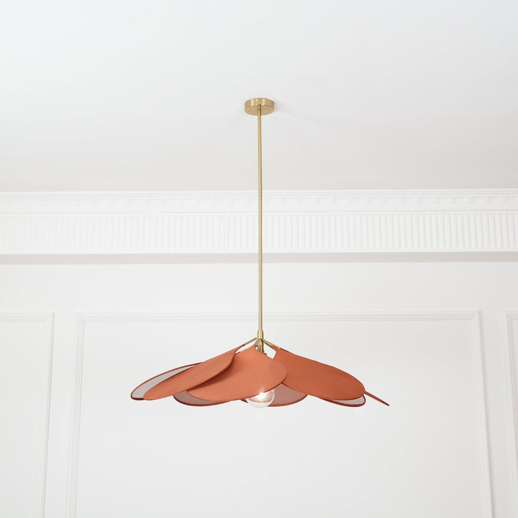 Seen from a distance, this Clérachic pendant lamp's terracotta petals hang high on their brass stem in a plain room.
