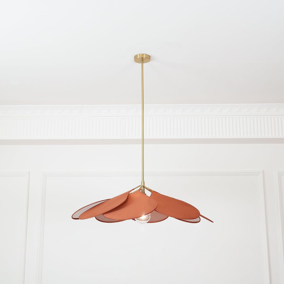 Seen from a distance, this Clérachic pendant lamp's terracotta petals hang high on their brass stem in a plain room.