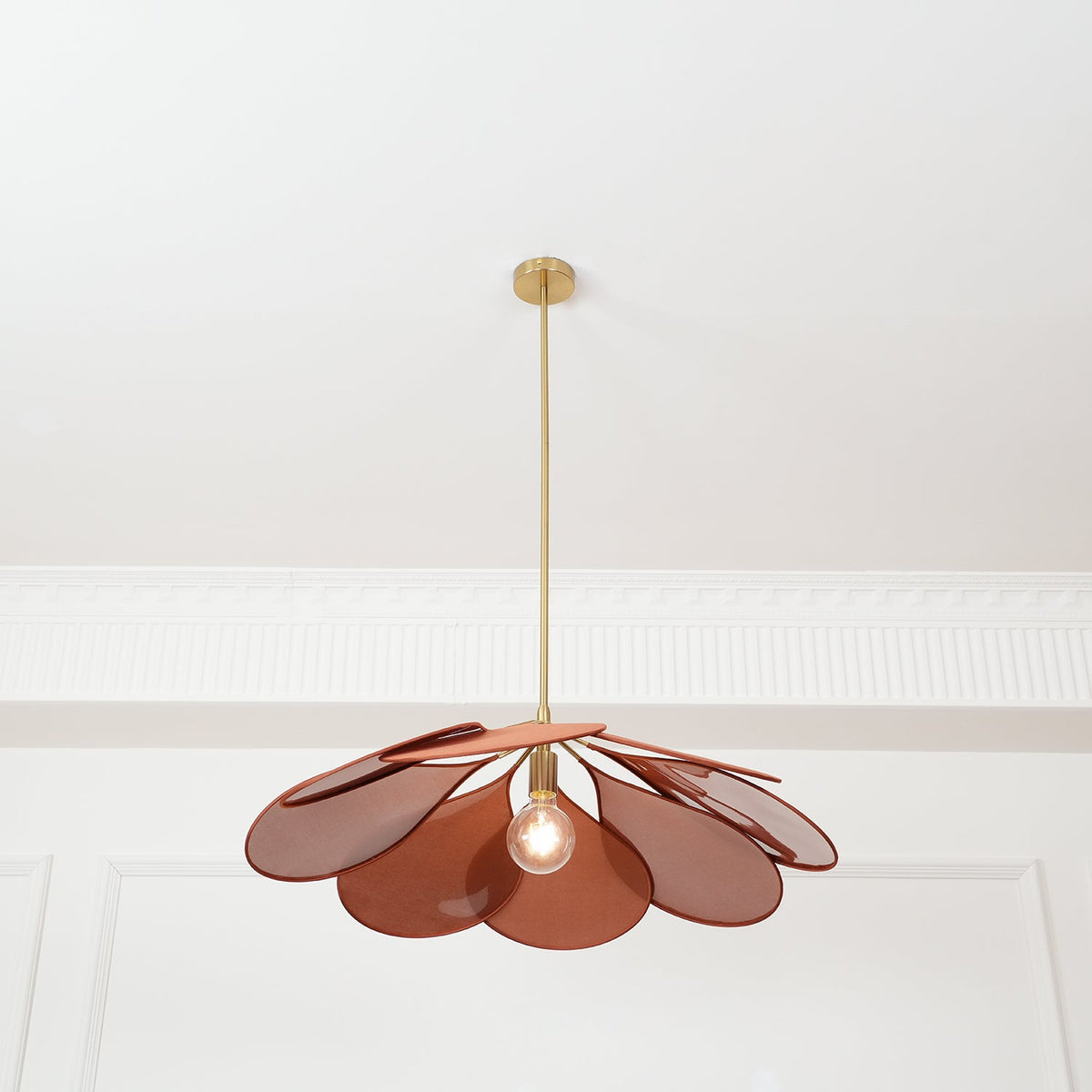 This Clérachic pendant lamp in terracotta petals hangs low, its bulb glowing softly beneath the fanned shade.