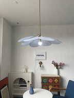This Clérachic pendant lamp in pale blue petals hangs lit above a white console styled with a small vase and figurine.
