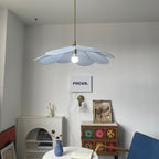This Clérachic pendant lamp in pale blue petals hangs lit above a white console and round table with a small vase.