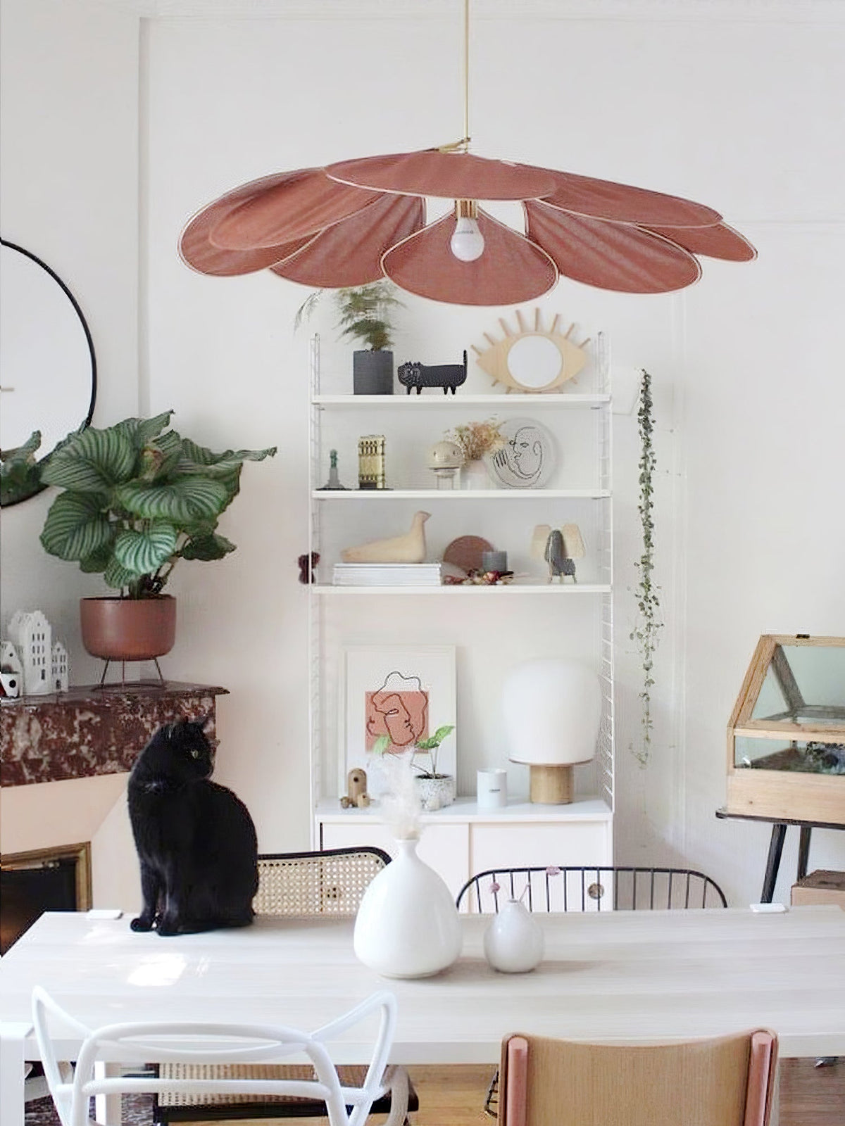 This Clérachic pendant lamp in terracotta petals hangs above a white dining table, with a black cat seated on a chair nearby.