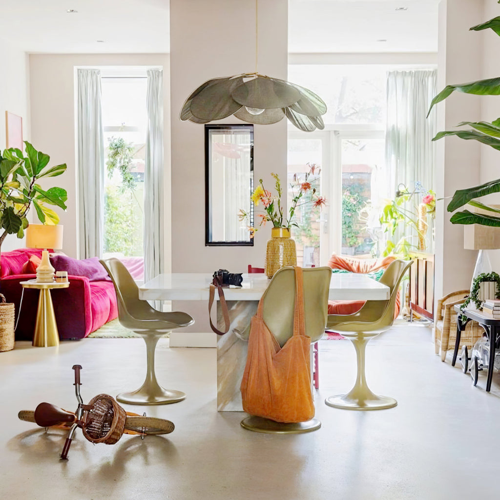 This Clérachic pendant lamp in a sage-green version hangs above a dining table with mismatched green, orange and gold chairs.