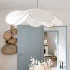 This Clérachic pendant lamp in white petals hangs beside a blue door in an entryway hung with woven baskets.