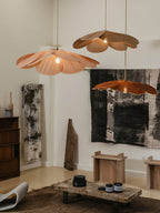 Two of these Clérachic pendant lamps, one terracotta and one copper, hang in a minimalist room with abstract wall art and a low bench.
