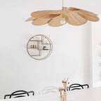 This Clérachic pendant lamp in tan petals hangs near a round gold wall shelf, above black-and-white bistro chairs.