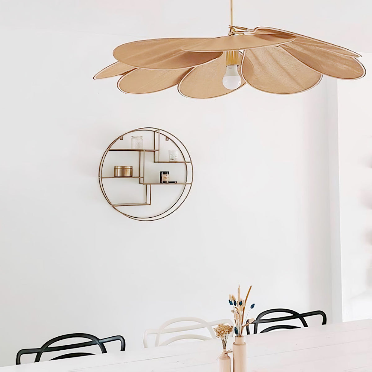 This Clérachic pendant lamp in tan petals hangs near a round gold wall shelf, above black-and-white bistro chairs.