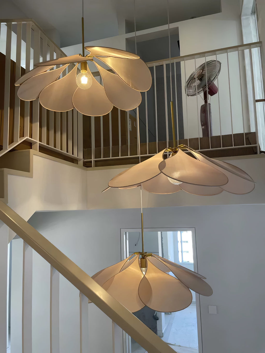 Three of these Clérachic pendant lamps in tan and cream petals hang at staggered heights above a loft staircase.