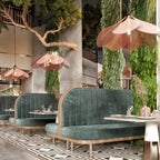 Several of these Clérachic pendant lamps in pink-toned petals hang above green velvet booth seating in a restaurant with a living plant wall.