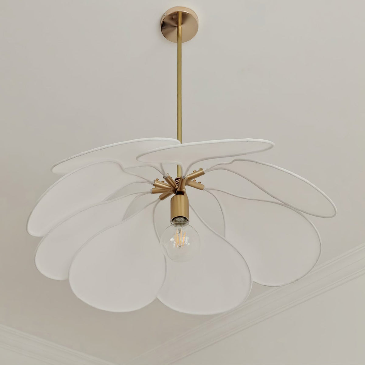 Studio shot of this Clérachic pendant lamp, its frosted white petals fanned out around a brass fitting and bare bulb.