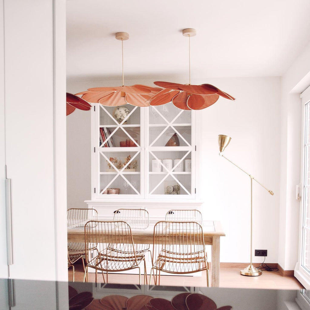 Two of these Clérachic pendant lamps in terracotta fabric petals hang above a dining table with rattan chairs and a glass-front cabinet.