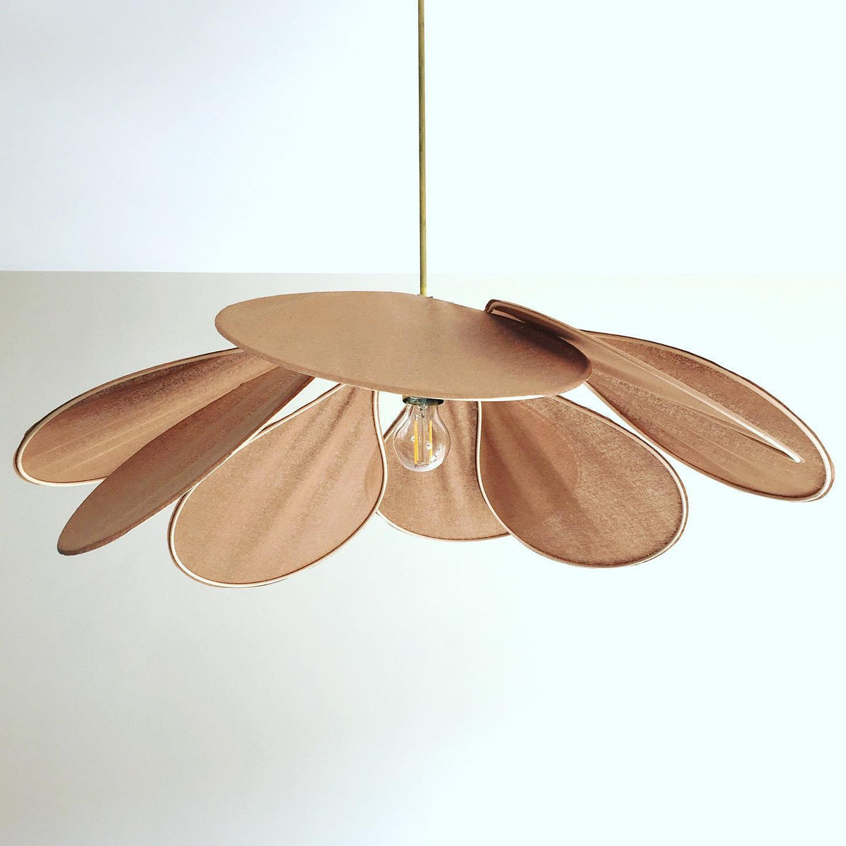 Studio shot of this Clérachic pendant lamp, its tan petals fanned into a wide dome around a central bulb on a brass stem.
