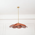 This Clérachic pendant lamp in terracotta petals hangs from a plain white ceiling, its bulb glowing beneath the fanned petals.