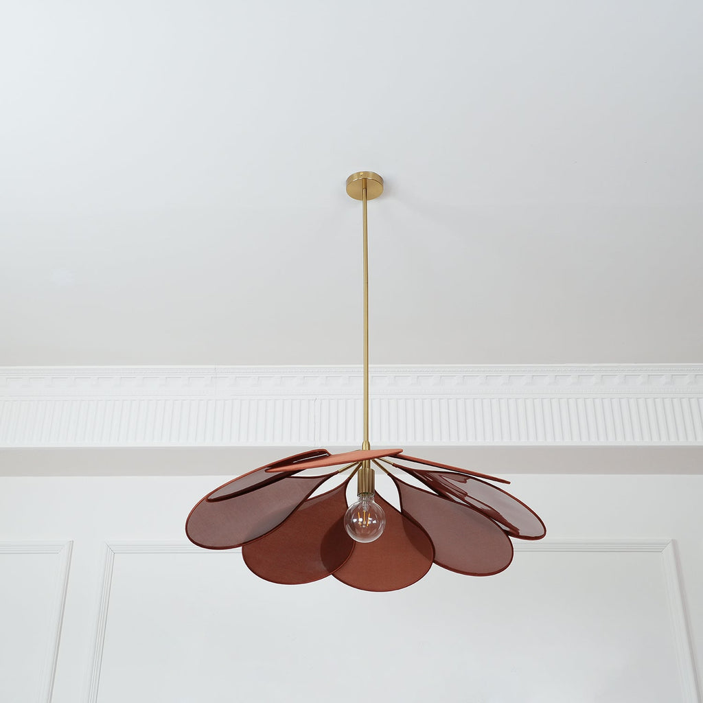 This Clérachic pendant lamp in deep red-brown petals hangs from a plain white ceiling with panel moulding.