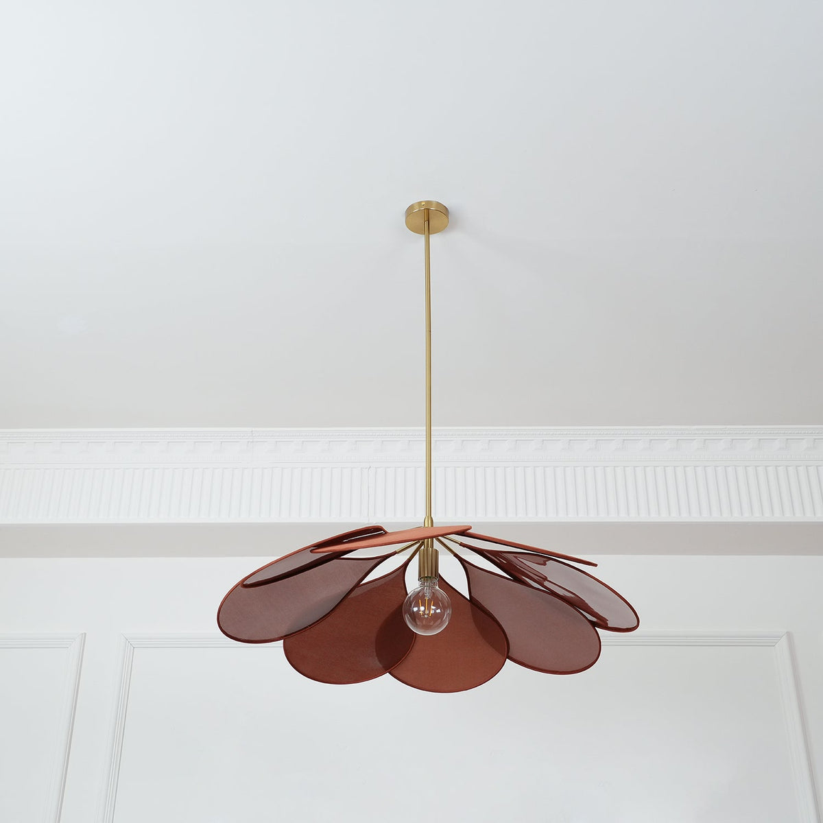 This Clérachic pendant lamp in deep red-brown petals hangs from a plain white ceiling with panel moulding.