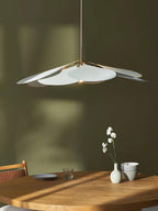 This Clérachic pendant lamp in white petals hangs against an olive-green wall, above a round table with orchids in a small vase.
