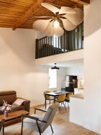 This Clérachic pendant lamp in tan petals hangs beneath a wood-beamed loft ceiling in an open-plan living and dining area.