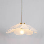 This Clérachic pendant lamp in white petals hangs lit against a plain grey wall, its bulb glowing at the centre.