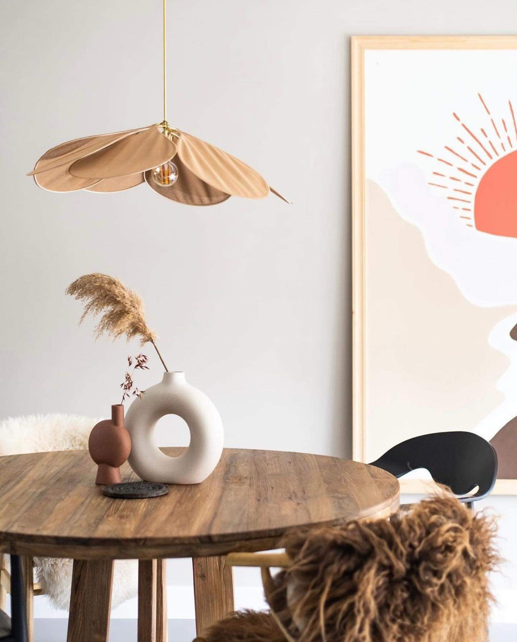 This Clérachic pendant lamp in tan petals hangs beside a round table with dried pampas grass, near a sun-print wall poster.