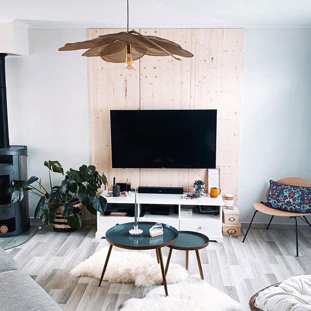 This Clérachic pendant lamp in dark taupe fabric petals hangs above a wood-panelled media wall with a mounted television.