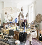 This Clérachic pendant lamp in cream fabric petals hangs above a dining table styled with pampas grass and string lights.