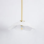 Studio shot of this Clérachic pendant lamp, its white petals fanned around a bare bulb on a brass stem.