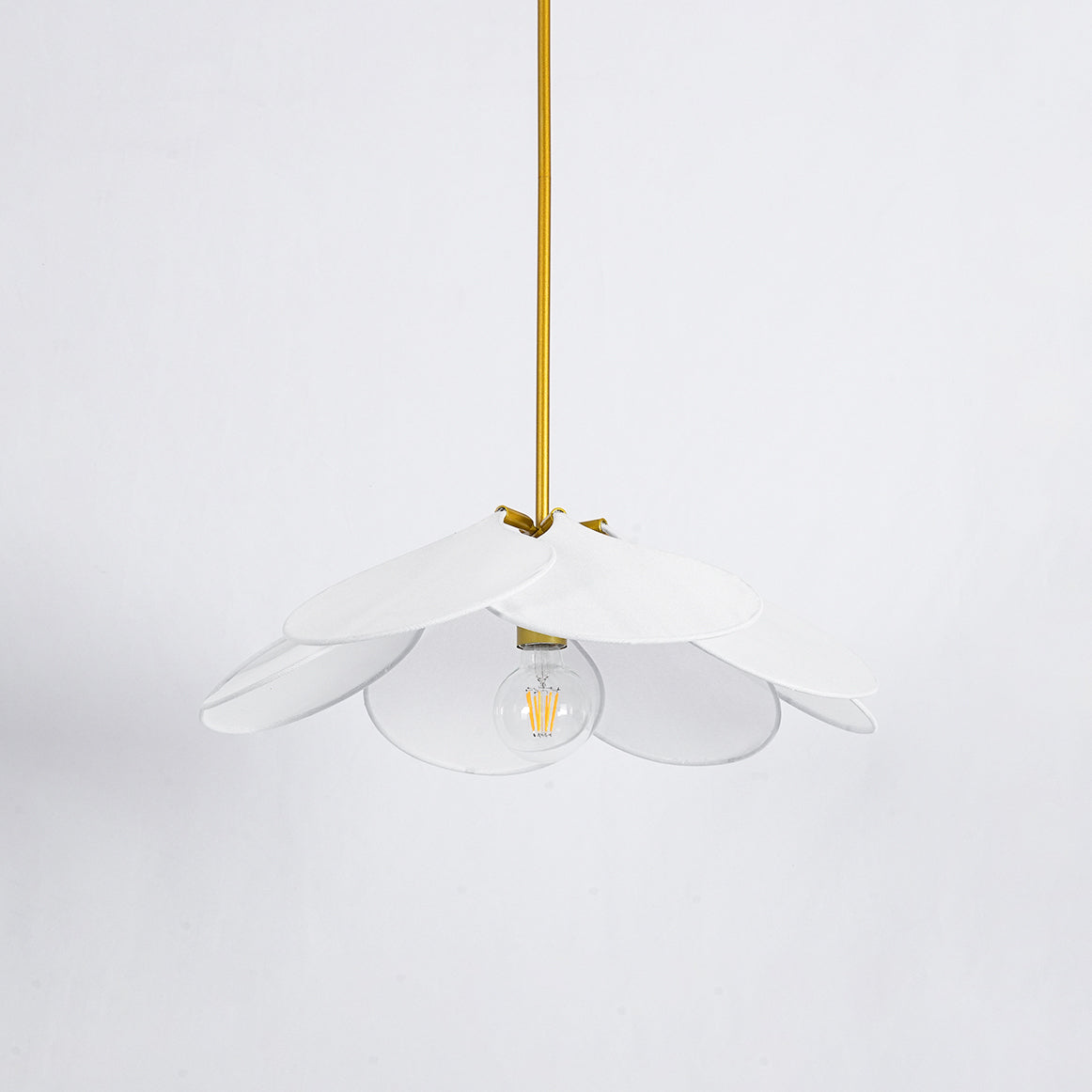 Studio shot of this Clérachic pendant lamp, its white petals fanned around a bare bulb on a brass stem.