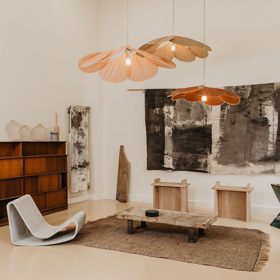 Two of these Clérachic fabric petal pendants in warm terracotta tones hang above a low table in a minimalist living room with abstract wall art.