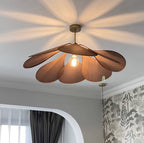This Clérachic pendant lamp in deep rust petals glows warmly from below, casting a starburst shadow across the ceiling.
