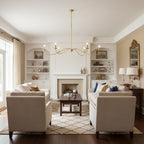 This gold Clérachic chandelier, hung without lampshades, spans a living room with two beige sofas and a fireplace mantel.